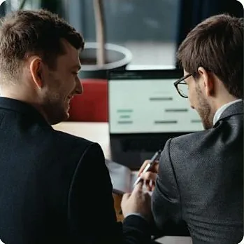Dvojica kolega razgovaraju uz laptop